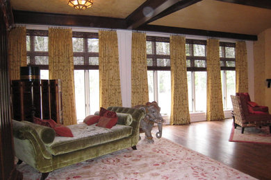 На фото: большая открытая гостиная комната в стиле фьюжн с белыми стенами, темным паркетным полом, стандартным камином, фасадом камина из плитки, телевизором на стене и коричневым полом с