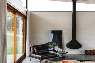 アデレードにあるコンテンポラリースタイルのおしゃれなリビング (白い壁、コンクリートの床、吊り下げ式暖炉、グレーの床) の写真