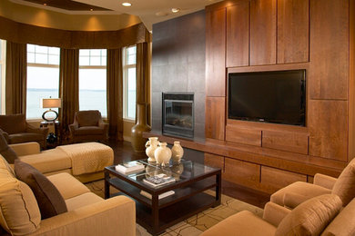 Example of a large classic enclosed dark wood floor living room design in Orange County with beige walls, a standard fireplace and a media wall