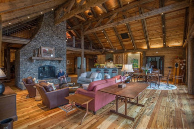 Living room - huge cottage loft-style medium tone wood floor and brown floor living room idea in Other with a two-sided fireplace and a stone fireplace