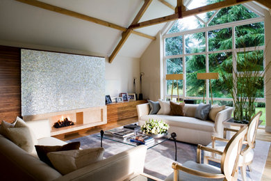 Photo of a modern living room in Other with light hardwood flooring, a concealed tv and exposed beams.