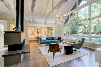 Example of a large trendy open concept medium tone wood floor living room design in Seattle with beige walls, a two-sided fireplace, a plaster fireplace and a tv stand