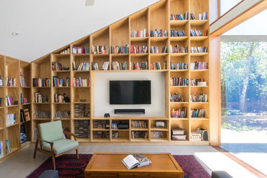Пример оригинального дизайна: изолированная гостиная комната в современном стиле с с книжными шкафами и полками, белыми стенами, телевизором на стене и серым полом