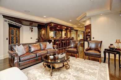 Foto de salón con barra de bar abierto clásico de tamaño medio con paredes grises, suelo de madera oscura, televisor colgado en la pared y suelo marrón