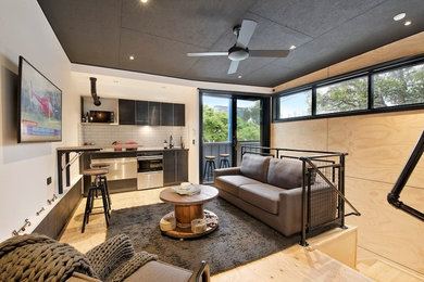 Immagine di un piccolo soggiorno industriale stile loft con pavimento in compensato e TV a parete