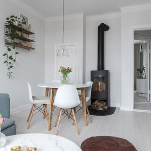 Bild på en skandinavisk matplats, med vita väggar, laminatgolv, en öppen vedspis och vitt golv