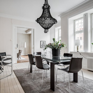 Nordisk inredning av en mellanstor separat matplats, med vita väggar, ljust trägolv och beiget golv