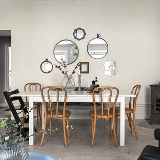 Inredning av en nordisk mellanstor matplats, med ljust trägolv, en öppen vedspis, en spiselkrans i metall, beige väggar och grått golv