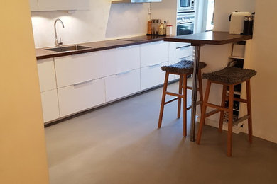 Esempio di una cucina abitabile moderna di medie dimensioni con pavimento in cemento