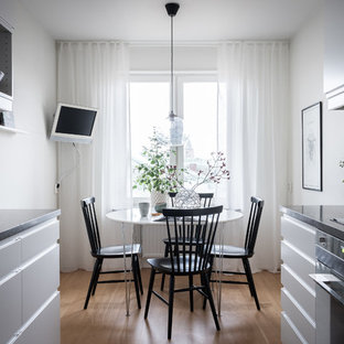 Idéer för minimalistiska matplatser, med vita väggar, mellanmörkt trägolv och beiget golv