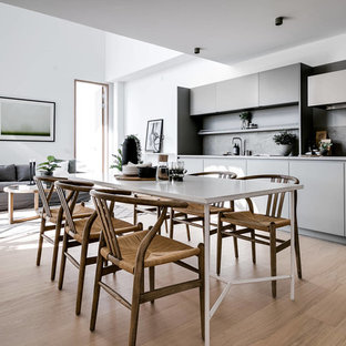 Minimalistisk inredning av ett mellanstort kök med matplats, med vita väggar, beiget golv och ljust trägolv