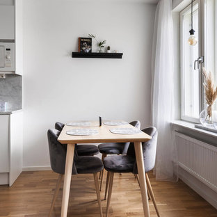 Skandinavisk inredning av ett kök med matplats, med vita väggar, mellanmörkt trägolv och brunt golv