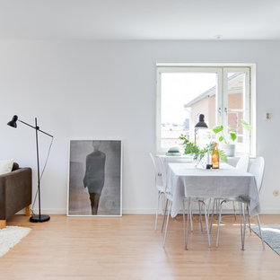 Skandinavisk inredning av en matplats med öppen planlösning, med vita väggar, ljust trägolv och beiget golv