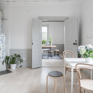 Foto på en nordisk matplats, med ljust trägolv, beiget golv, vita väggar, en öppen hörnspis och en spiselkrans i trä