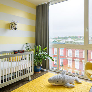 Foto di una cameretta per neonati neutra design con pareti gialle, parquet scuro e pavimento marrone