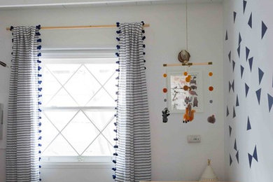 This is an example of a medium sized bohemian nursery for boys in Los Angeles with white walls, carpet and grey floors.