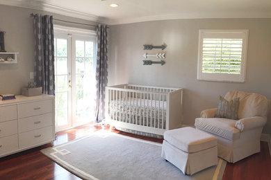 Idée de décoration pour une chambre de bébé garçon de taille moyenne avec un mur gris et un sol en bois brun.