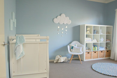 Ejemplo de habitación de bebé neutra minimalista grande con paredes azules y suelo de madera clara