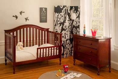 Ejemplo de habitación de bebé neutra clásica de tamaño medio con paredes blancas y suelo de madera en tonos medios