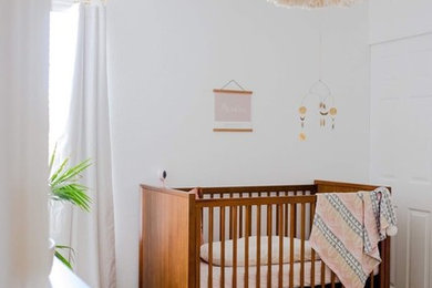 Diseño de habitación de bebé niña ecléctica de tamaño medio con paredes blancas, suelo de madera oscura y suelo marrón