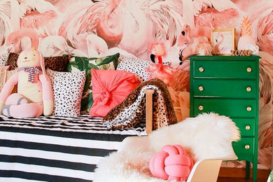 Foto de habitación de bebé niña exótica con paredes rosas, suelo de madera en tonos medios y suelo marrón
