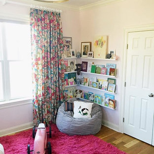 Imagen de habitación de bebé niña tradicional renovada, de tamaño medio, con paredes rosas y suelo de madera en tonos medios