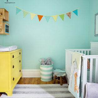 Immagine di una piccola cameretta per neonati neutra con pareti verdi, parquet chiaro e pavimento giallo