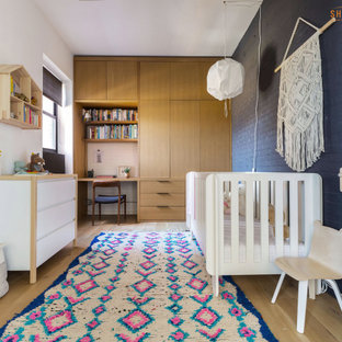Ispirazione per una cameretta per neonati neutra moderna di medie dimensioni con pareti grigie, pavimento in laminato, pavimento beige e pareti in mattoni