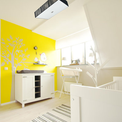 Nursery - contemporary gender-neutral light wood floor and beige floor nursery idea in Amsterdam with yellow walls