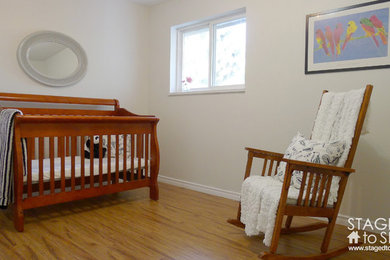 Imagen de habitación de bebé tradicional renovada pequeña con paredes blancas y suelo laminado
