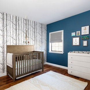 Foto de habitación de bebé neutra actual, de tamaño medio, con paredes azules, suelo de madera oscura y suelo marrón