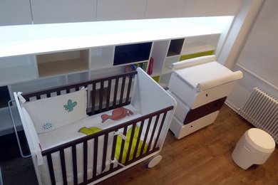 Esempio di una piccola cameretta per neonati neutra minimalista con pareti bianche e pavimento in legno massello medio