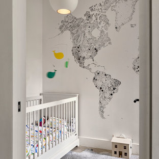 Contemporary gender neutral nursery in London with white walls, medium hardwood flooring and grey floors.