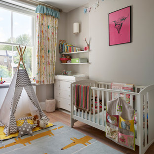 Design ideas for a contemporary gender neutral nursery in London with grey walls and light hardwood flooring.