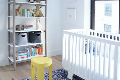 Imagen de habitación de bebé niño moderna de tamaño medio con paredes blancas, suelo de madera en tonos medios y suelo marrón