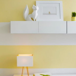 Foto di una cameretta per neonati neutra design con pavimento in legno massello medio, pavimento marrone e pareti gialle