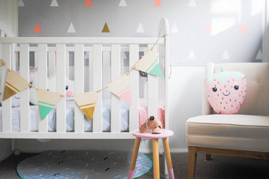 Ejemplo de habitación de bebé niña tradicional renovada de tamaño medio con paredes grises y moqueta