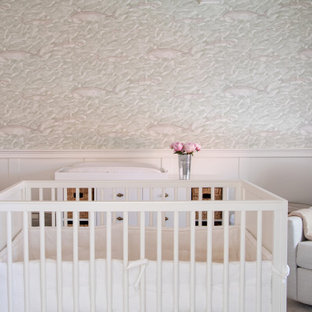 Cette photo montre une chambre de bébé neutre chic de taille moyenne avec un mur blanc, un sol en bois clair, un sol beige, un plafond en poutres apparentes et boiseries.