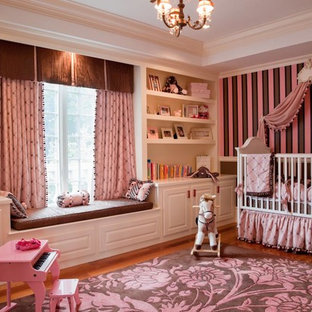 Immagine di un'ampia cameretta per neonata classica con pareti rosa e pavimento in legno massello medio