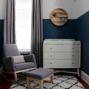 Mid-sized minimalist boy medium tone wood floor nursery photo in Philadelphia with blue walls