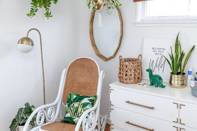 Imagen de habitación de bebé neutra exótica con paredes blancas y suelo de madera en tonos medios