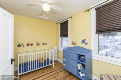Small nursery for boys in Baltimore with yellow walls and light hardwood flooring.