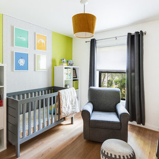 Nursery - modern gender-neutral light wood floor nursery idea in Denver with green walls