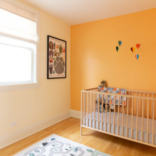 Immagine di una cameretta per neonati neutra nordica con pareti arancioni, parquet chiaro e pavimento giallo