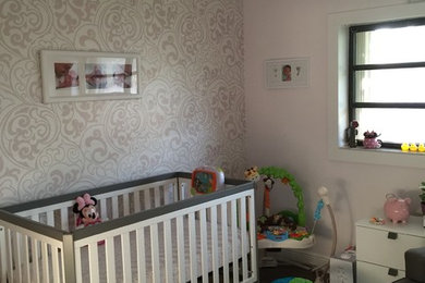 Photo of a medium sized contemporary nursery for girls in Miami with pink walls, laminate floors and brown floors.