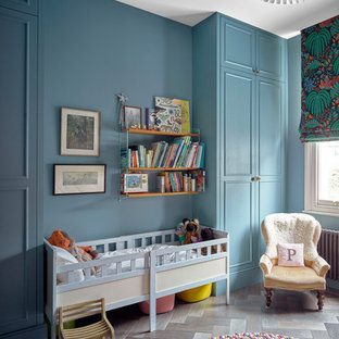 Idee per una cameretta per neonati neutra chic di medie dimensioni con pareti blu, parquet scuro e pavimento marrone