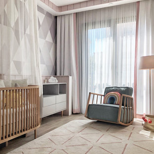 Ispirazione per una cameretta per neonata minimal di medie dimensioni con pavimento in laminato, pareti multicolore e carta da parati