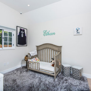 Example of a mid-sized classic boy light wood floor, brown floor and vaulted ceiling nursery design in Los Angeles with beige walls