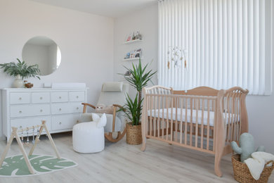 Photo of a small modern gender neutral nursery in San Francisco with white walls and light hardwood flooring.