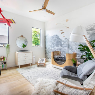 Diseño de habitación de bebé neutra actual con paredes blancas, suelo de madera clara y suelo beige